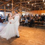 A bride and groom share their first dance at their wedding reception in a barn.