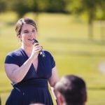 A woman is speaking into a microphone during a wedding ceremony.