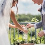 The bride is wearing a white dress at the wedding ceremony.