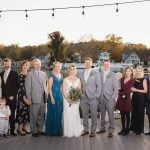 A wedding party posing for a portrait on a dock.