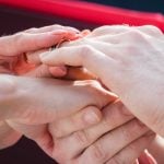 A man and woman participating in a wedding ceremony by exchanging rings.