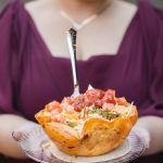 A woman holding a bowl of tacos at a wedding.