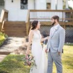 A wedding portrait of a bride and groom standing in front of a house.