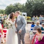 A couple shares a kiss during their outdoor wedding ceremony.