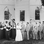 A black and white portrait of a wedding party in front of a church.