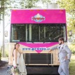 A wedding portrait next to a pink food truck.