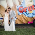 A bride and groom pose for a wedding portrait in front of a gruto's ice cream truck.