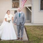 A portrait of a bride and groom in front of a house.