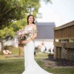 A wedding portrait of a bride holding her bouquet in front of a barn.