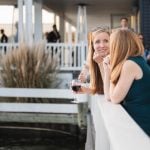 Two women enjoying wine at a wedding reception.