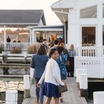 A wedding party walking down a dock.