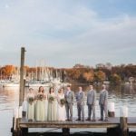 A portrait of a wedding party standing on a dock.