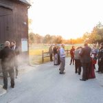 A group of people celebrating at a wedding reception in front of a barn.