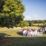 A wedding ceremony in a field surrounded by trees.