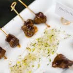 Skewers of meat on a white plate showcasing intricate details.