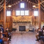 A wedding ceremony with string lights in a barn.