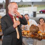 A man speaking into a microphone at a wedding reception.