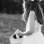 A little girl in a flower crown participating in a wedding ceremony, holding a basket.