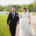 A wedding portrait of a bride and groom walking down a path in a park.