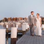 A wedding portrait of a bride and groom standing on a dock at a marina.