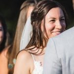 A bride and groom smile at each other during their wedding ceremony.