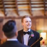 A groom smiles at the bride during their wedding ceremony.