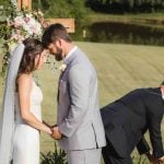 A wedding ceremony with a bride and groom standing next to a cross in a field.