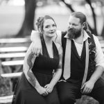 A black and white wedding portrait of a couple sitting on a bench.