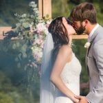 A couple shares a passionate kiss during their wedding ceremony.