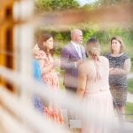 A candid wedding preparation moment captured with a group of people standing in front of a window.