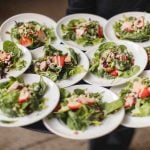 At a wedding, a person showcases the intricate details by skillfully holding plates of salads on a tray.