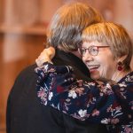 An older woman is hugging another woman at a wedding reception.