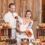 A couple cutting their wedding cake at their reception in a barn.