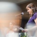 A woman speaking into a microphone at a wedding reception.