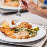 A woman is holding a fork and eating with attention to details.