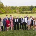 A group of people posing for a wedding portrait in front of a field.