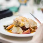 A person is eating a plate of food with wedding details.