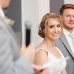 A bride and groom smiling at each other during their wedding ceremony.