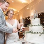 A bride and groom enjoying their wedding reception, cutting into their beautiful wedding cake.