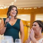 A woman is speaking into a microphone at a wedding reception.