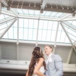 A bride and groom share their first dance at their wedding reception under a skylight.