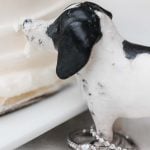 A wedding cake topper featuring a dachshund with a ring.