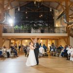 A bride and groom's first dance during their wedding reception in a barn.