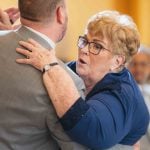 A woman is hugging an older man at a wedding reception.