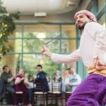 A man in a purple dress dancing at a wedding reception.