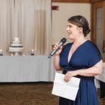 A woman speaking into a microphone at a wedding reception.