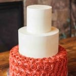 A wedding cake adorned with red roses.