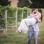 A bride and groom embracing each other in a vineyard for their wedding portrait.