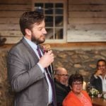 A man speaking into a microphone at a wedding reception.