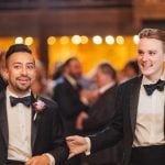 Two men in tuxedos walking down the wedding aisle.